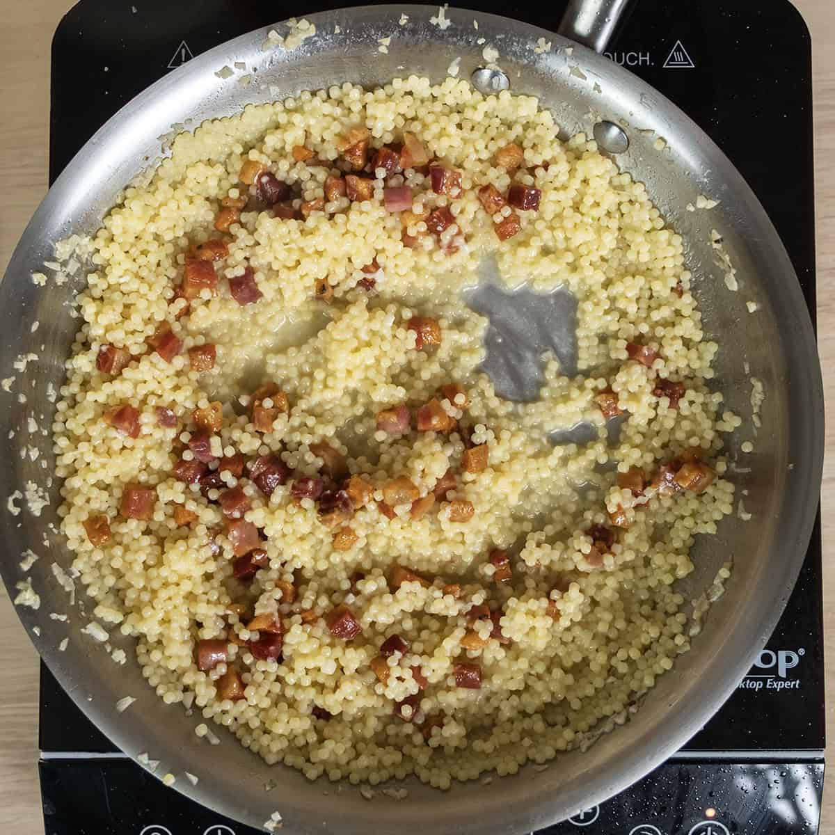 Pancetta and parmigiana added to the pan with pastina.