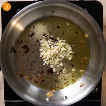 Garlic sauteing in a pan with olive oil.