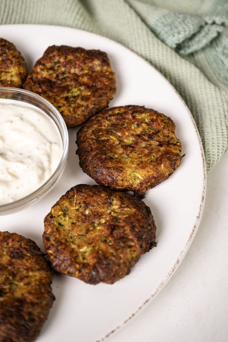 A plate of zucchini fritters with a dip.