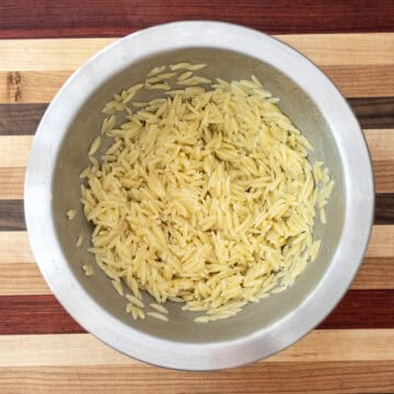 Combining orzo with olive oil to cool.
