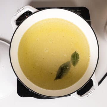 Whisking together cold water, olive oil, salt, bay leaves, and polenta.