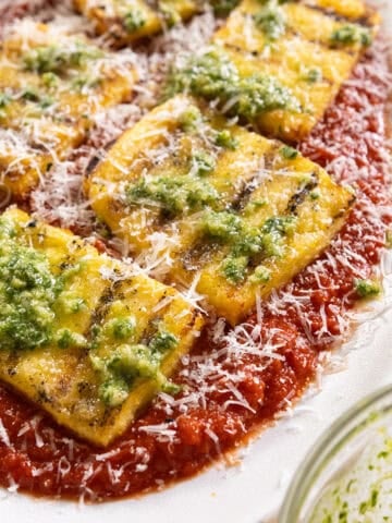 Grilled polenta on marinara topped with pesto and parmigiano.