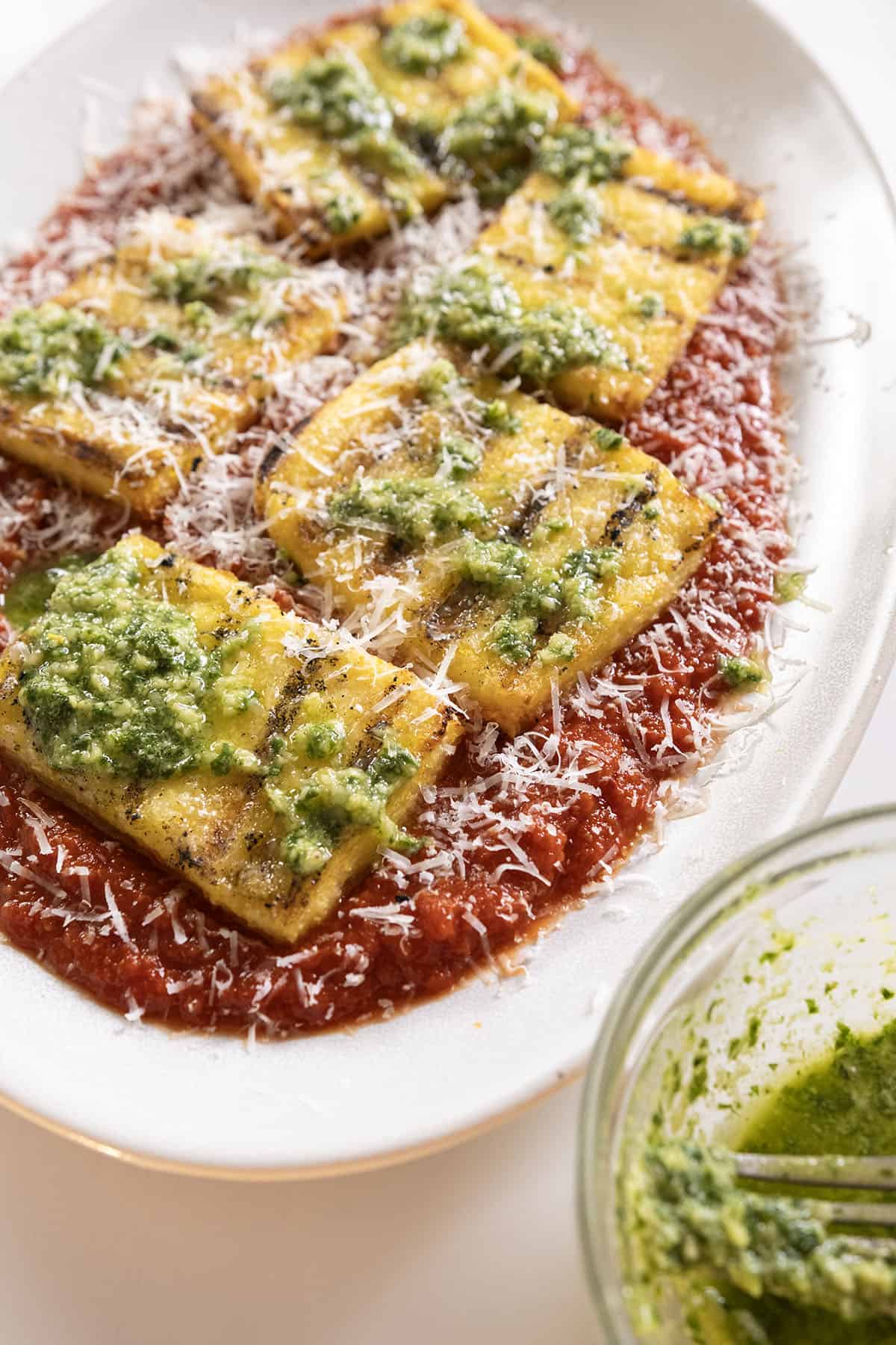 Grilled polenta on marinara topped with pesto and parmigiano.