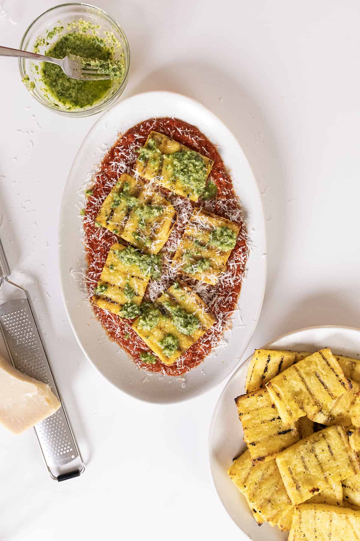 Grilled polenta on marinara topped with pesto and parmigiano.