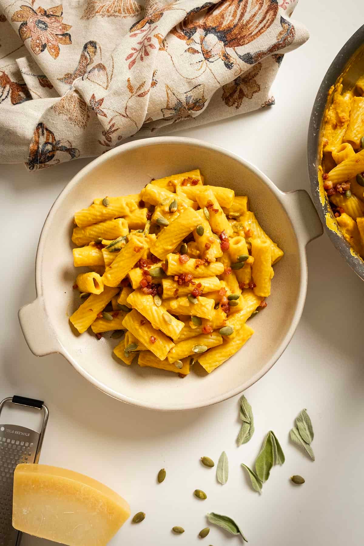 Pumpkin pasta in a bowl topped with pumpkin seeds and pancetta.