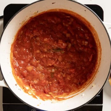 Marinara simmering in a pot with onions and garlic.