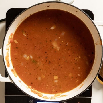 Chicken broth added to marinara and meat in a pot.