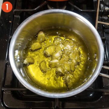Simmering garlic in a pot of oil.