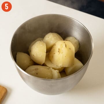 Softened and boiled potatoes in a mixing bowl.
