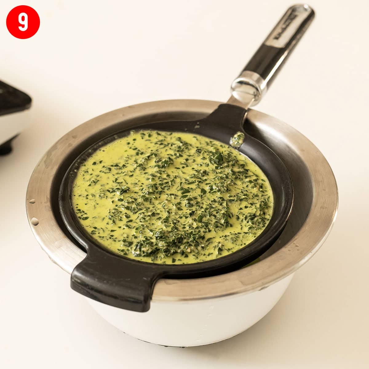 Straining kale pesto in a mesh strainer.