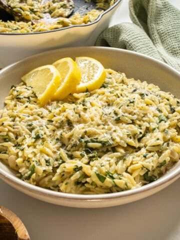 Lemon spinach orzo in a bowl topped with lemon garnish.