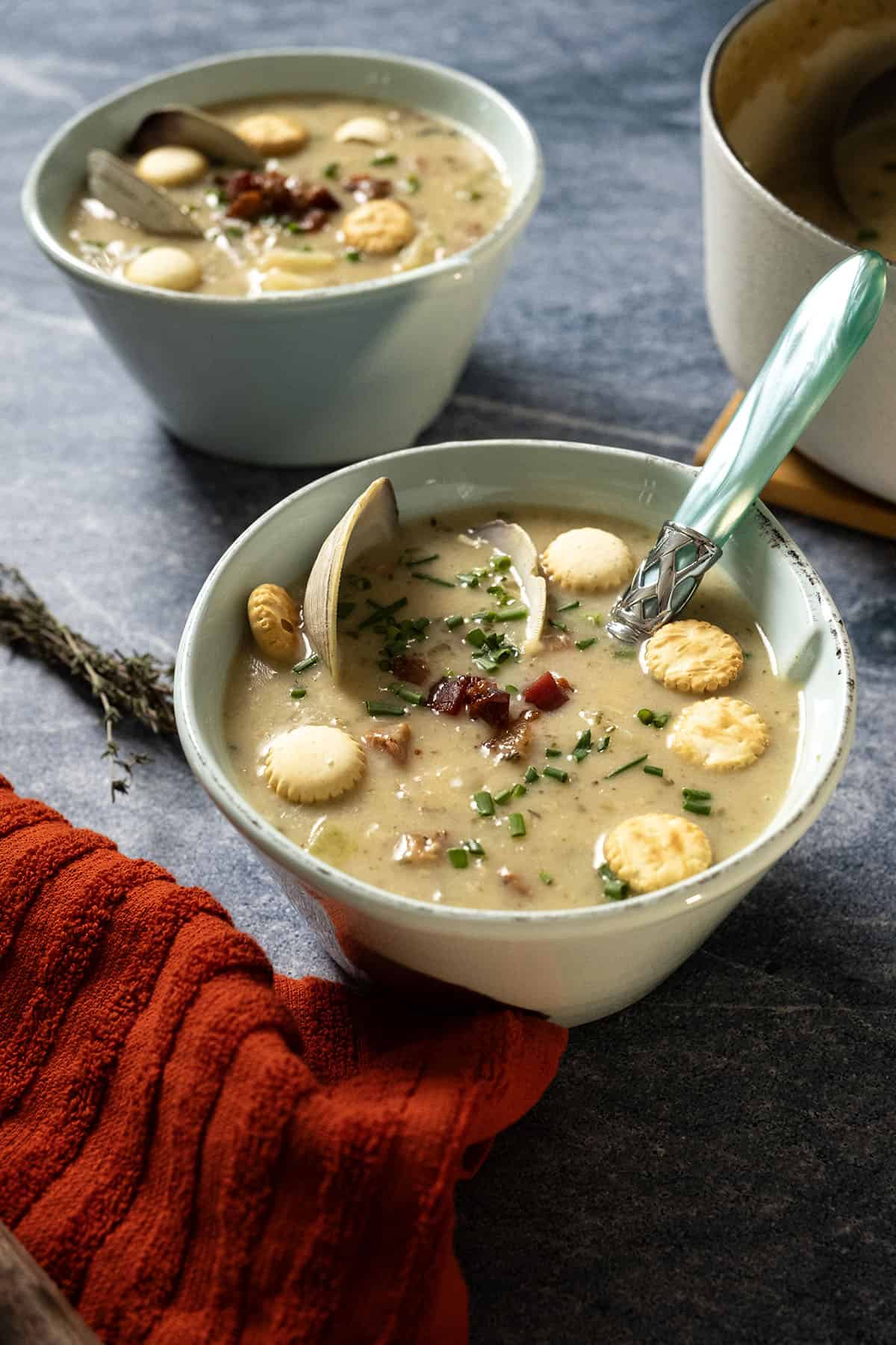 New england clam chowder in a bowl garnished with chives and oyster crackers.