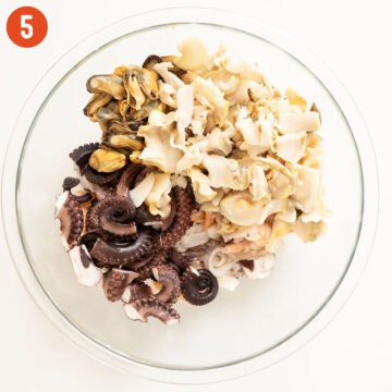 Combining seafood in a bowl.