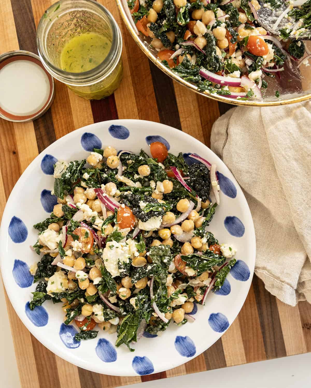 Garbanzo bean kale salad in a bowl with mason jar of extra dressing.