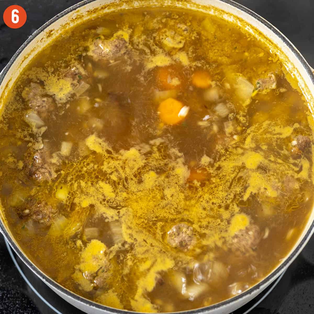 Simmering soup with meatballs and orzo.