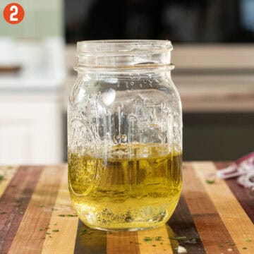 Olive oil, dijon, and parsley combined in a mason jar.
