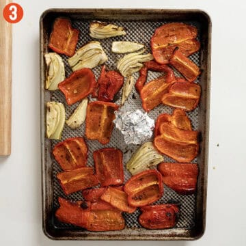 Roasted red peppers, fennel, and garlic on a sheet pan with olive oil, salt, and pepper.