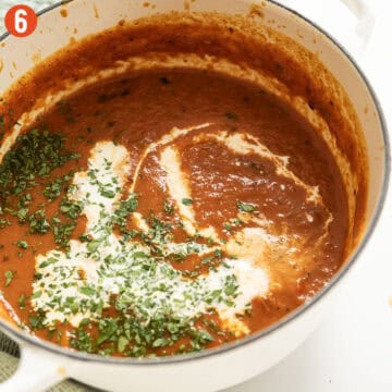 Drizzling cream in soup and garnishing with parsley.