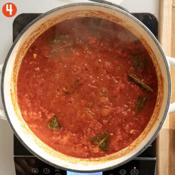 Simmering tomatoes and basil in a pan.