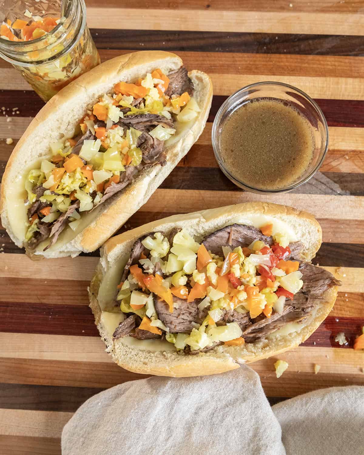 Italian beef sandwiches with au jus topped with giardiniera.