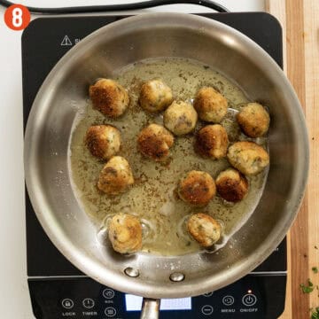 Golden-brown eggplant meatballs in a frying pan.