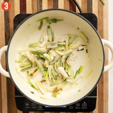 Sauteing spring onions in a pot.