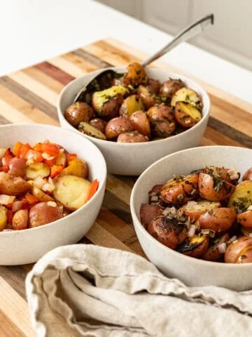 Foil potatoes 3 ways on a cutting board.