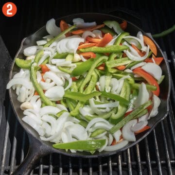 Peppers and onions in a cast iron pan.