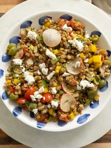 A cold Mediterranean lentil salad topped with goat cheese in a bowl.