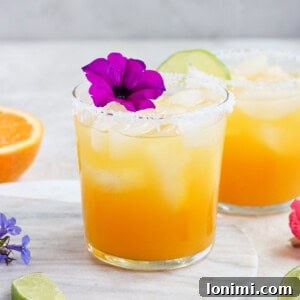 Passion fruit margarita with salt on the rim and a purple flower garnish