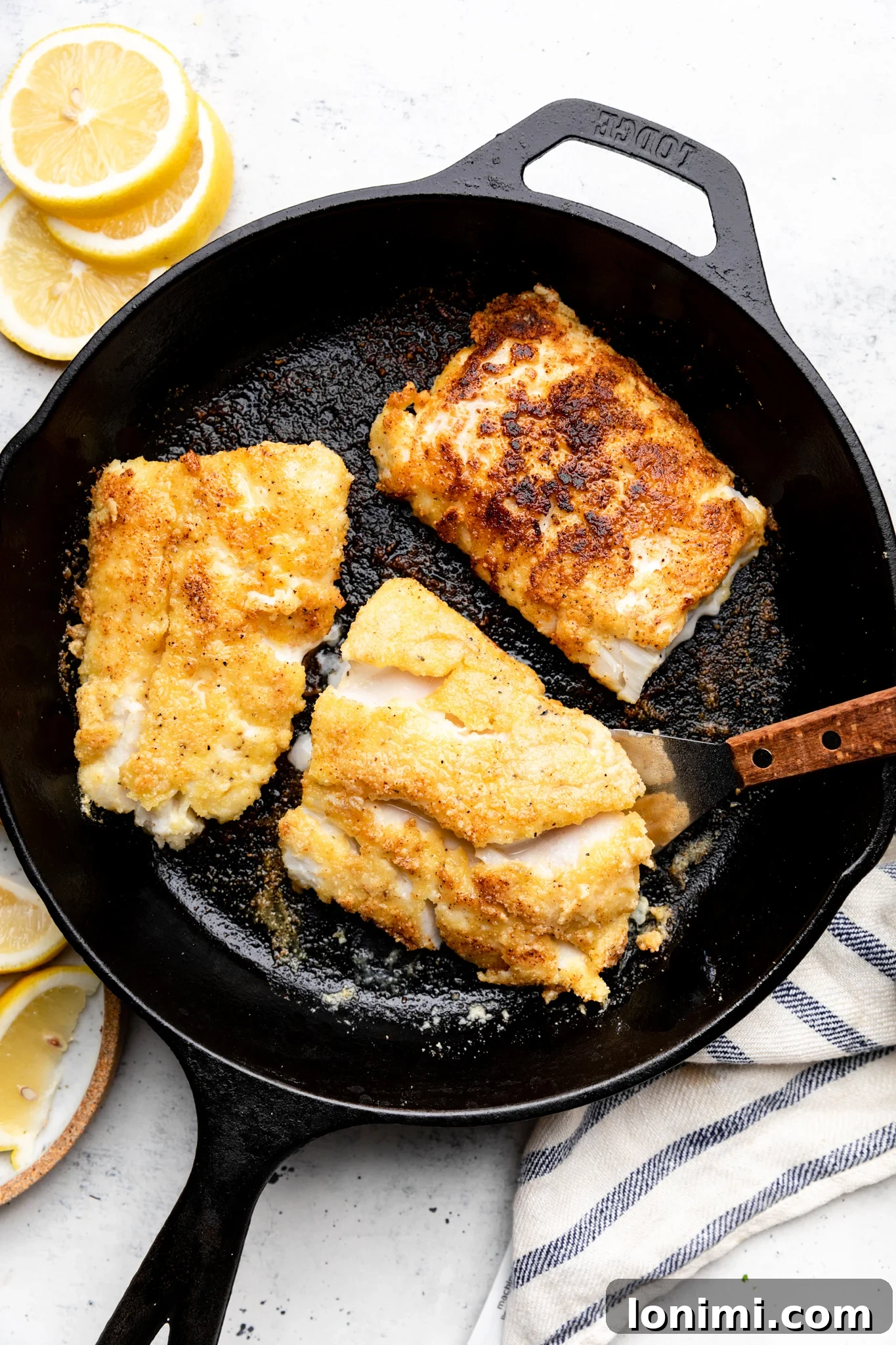 fried cod fillets in a cast iron pan