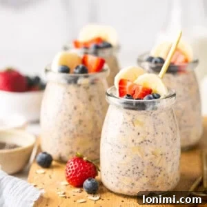protein overnight oats in mini glass jars on a wooden cutting board topped with fruit