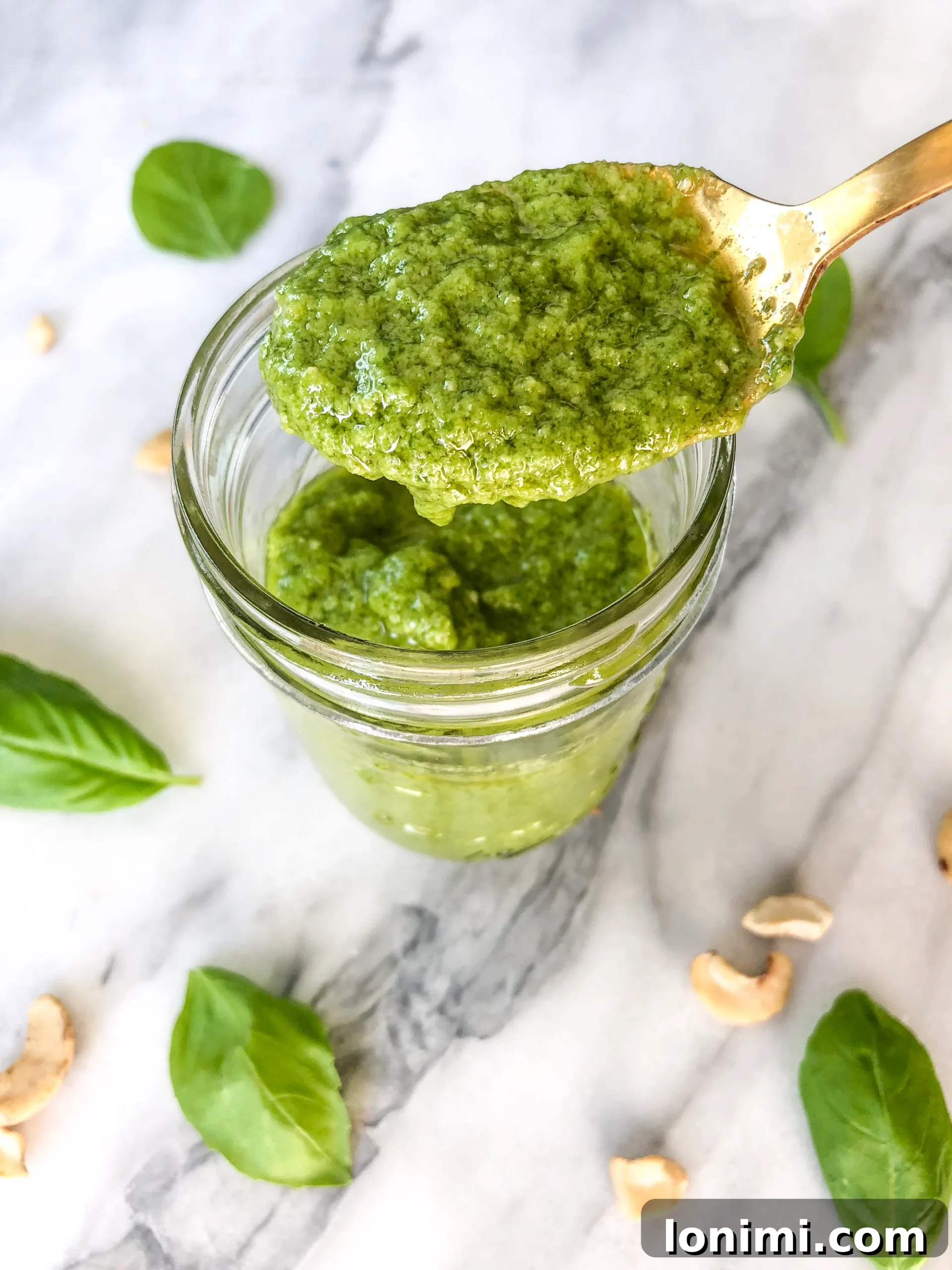 Freshly blended vibrant green cashew pesto in a small bowl, garnished with a basil leaf.