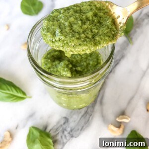 A small bowl of fresh cashew pesto, ready to be served, garnished with a sprig of basil.