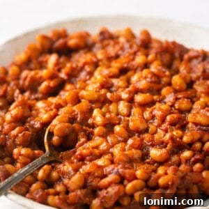 Nutritious Bean Bake 7 baked beans in a white bowl with a silver spoon
