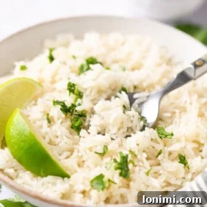 Fluffy and Fragrant Instant Pot Coconut Rice 6 instant pot coconut rice topped with cilantro and a wedge of lime in a white bowl with a silver spoon
