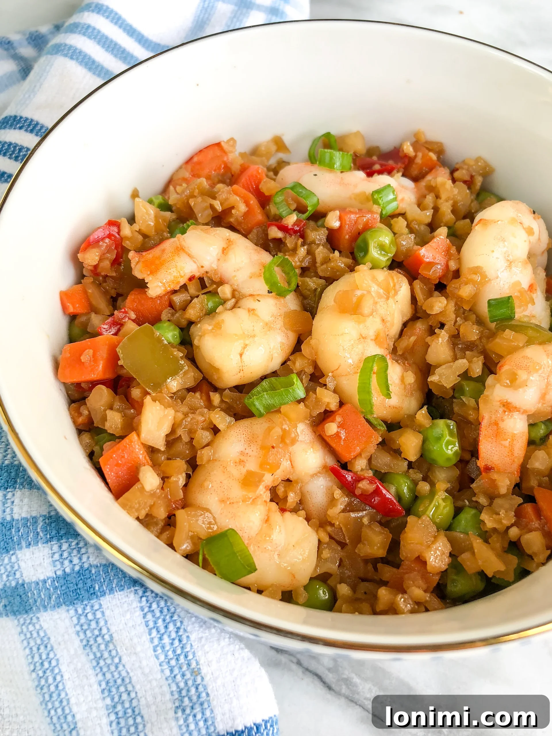Grain-Free Shrimp Stir-Fry 3 A close-up shot of the Paleo Shrimp Fried Rice cooking in a large skillet, showing colorful vegetables and shrimp.