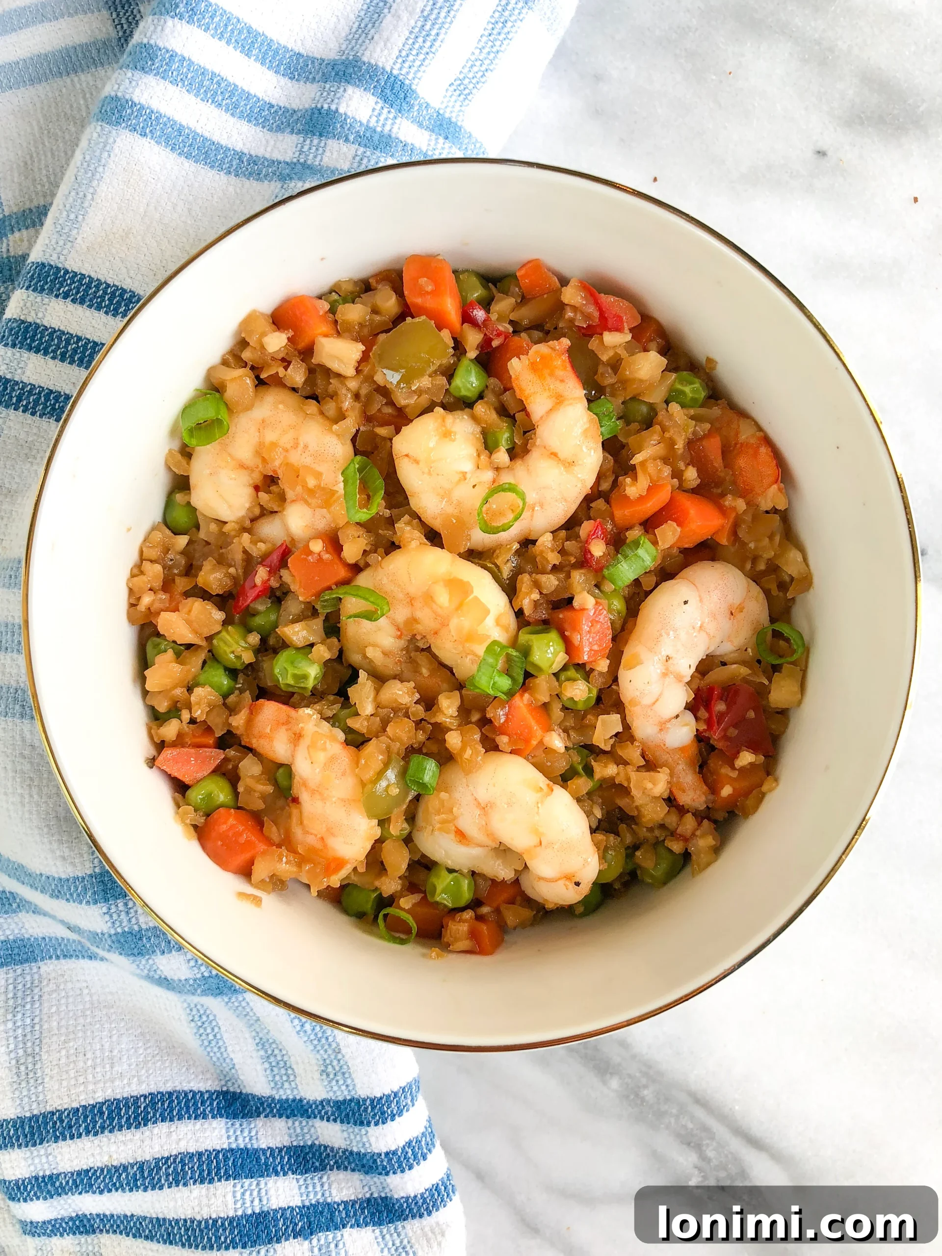 Grain-Free Shrimp Stir-Fry 4 A full bowl of Paleo Shrimp Fried Rice, garnished with green onions, ready to be enjoyed.