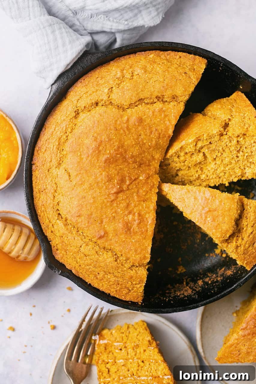 Golden Sweet Potato Cornbread 2 A cast iron pan with golden slices of sweet potato cornbread, a single slice rests on a white plate with a silver fork, highlighting its tender texture and crispy edges. Perfect for a cozy autumn meal.