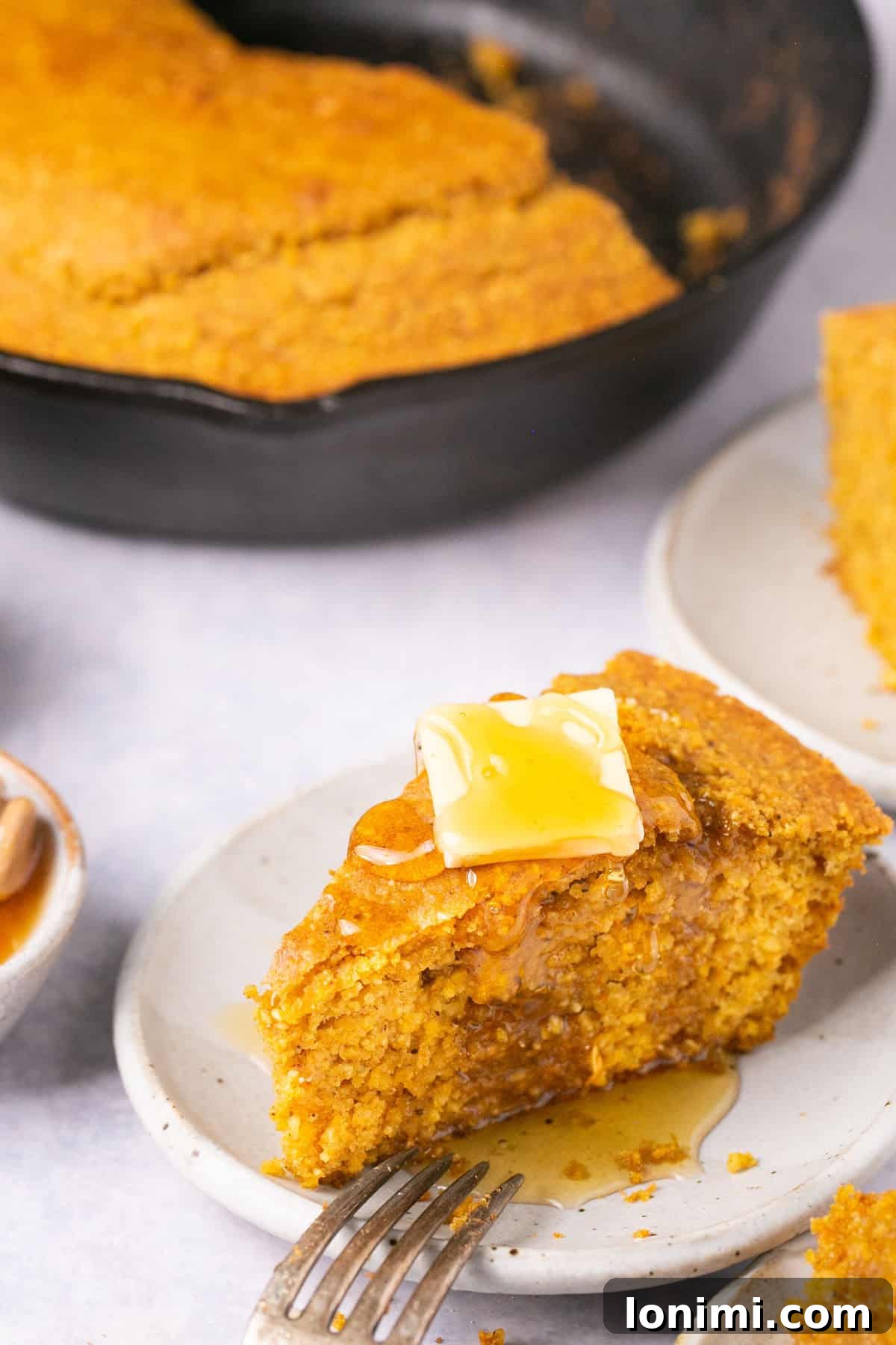 Golden Sweet Potato Cornbread 7 A mouthwatering close-up shot of a slice of sweet potato cornbread, generously drizzled with golden honey and melted butter, highlighting its moist interior and inviting textures.