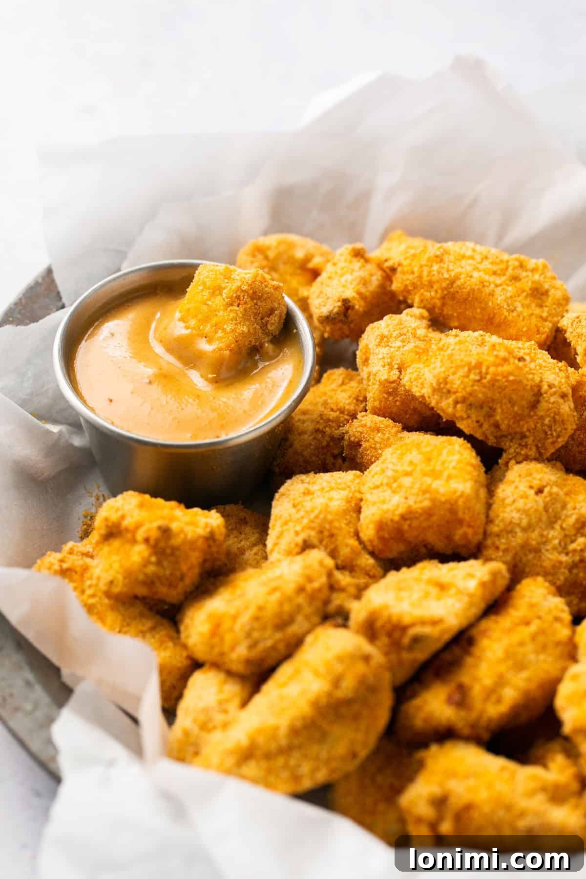 Crispy Air Fryer Chick-fil-A Style Nuggets with Homemade Sauce 6 Air fryer chicken nuggets in a basket, with one being dipped into the homemade Chick-fil-A sauce.