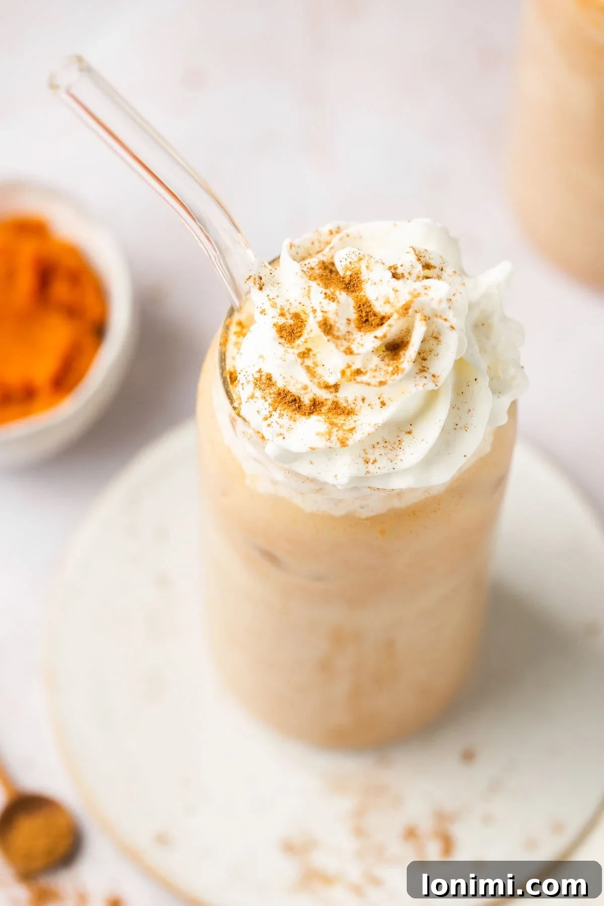 an overhead shot of a iced coffee drink topped with whipped cream and pumpkin pie spice