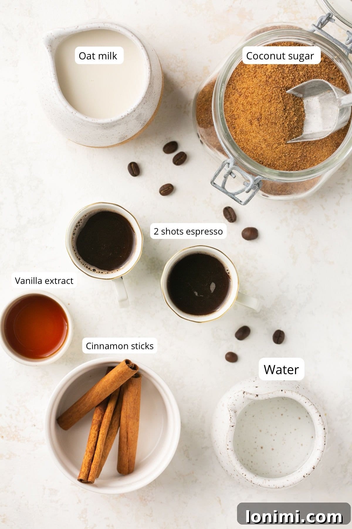 Small bowls displaying the essential ingredients for brown sugar shaken espresso: espresso, oat milk, vanilla extract, cinnamon stick, and coconut sugar.