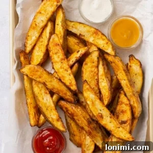 air fryer potato wedges in a basket with 3 dipping sauces