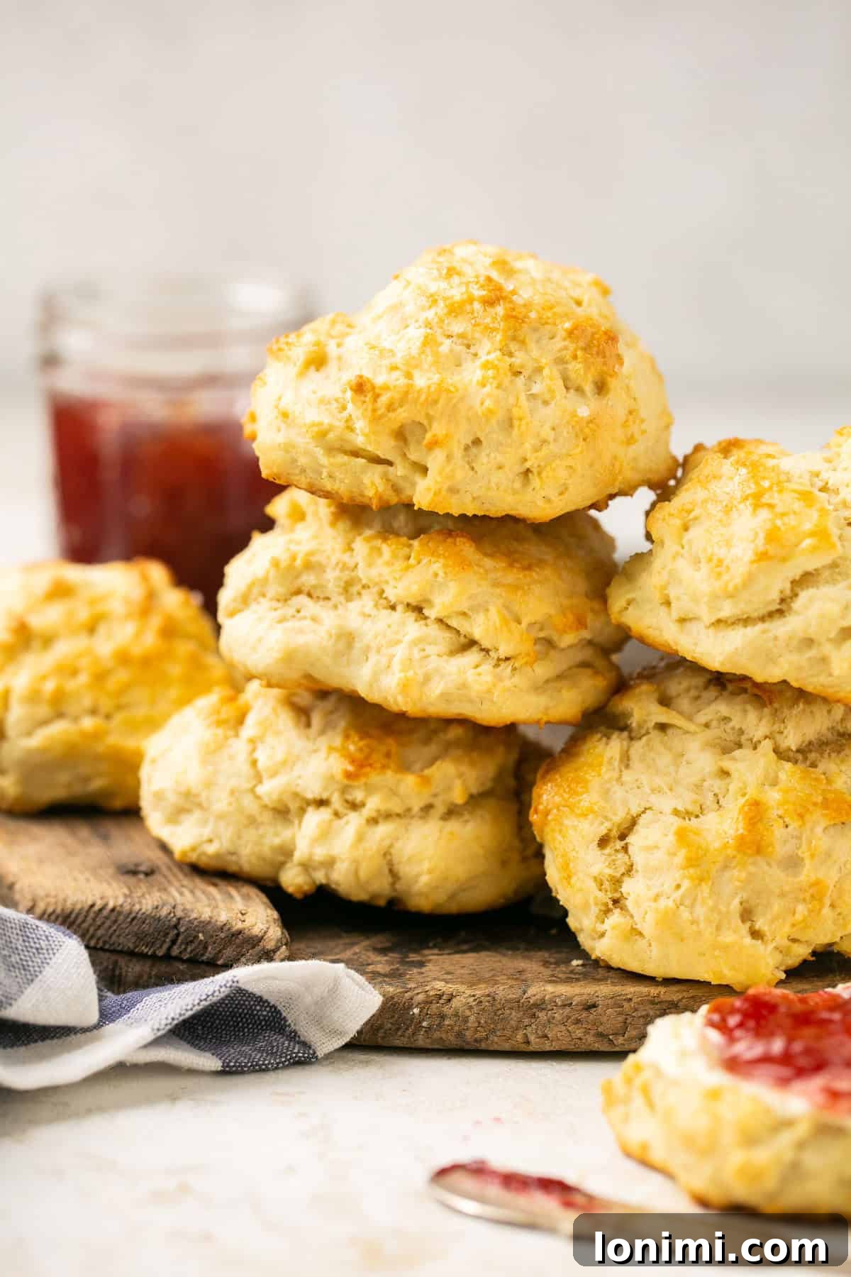 fluffy gluten-free biscuits stacked on a cutting board with jam in the background, ready to be enjoyed