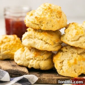 fluffy gluten-free biscuits stacked on a cutting board with jam in the background
