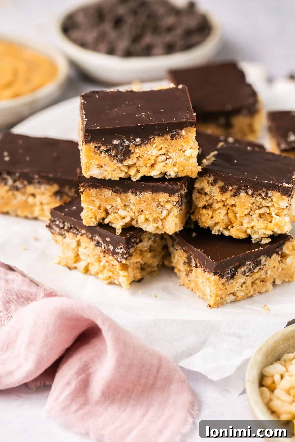 a stack of chocolate covered rice krispie treats on parchment paper
