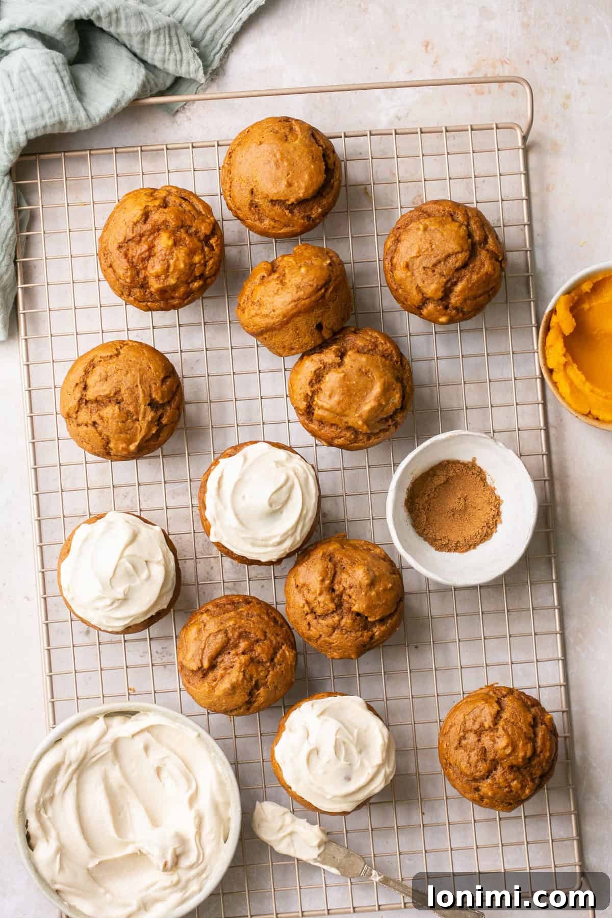 Simple Pumpkin Muffins with Velvety Dairy-Free Cream Cheese Frosting 6 An overhead shot of warm pumpkin muffins cooling on a baking rack, some already adorned with creamy frosting.
