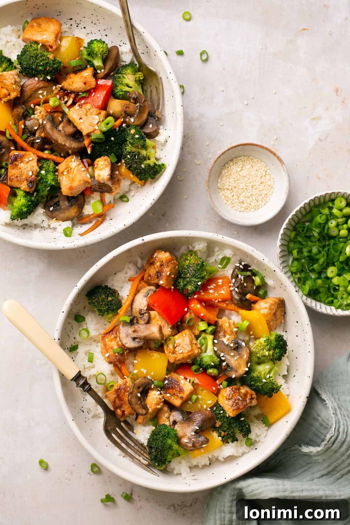Effortless 30-Minute Gluten-Free Teriyaki Salmon Stir-Fry 8 An overhead shot of two bowls of stir fry with vegetables, rice, and salmon.