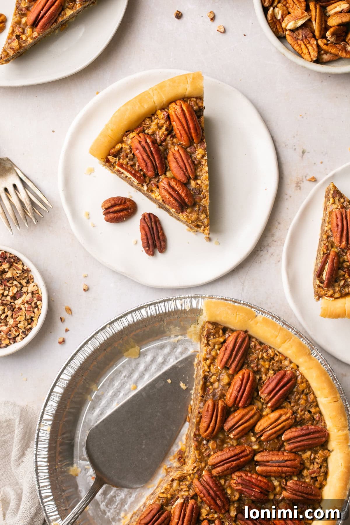 An alluring overhead shot of a delicious slice of pecan pie, beautifully garnished with pecan halves, resting beside a foil pie plate with a portion of the pie already savored.